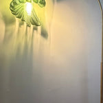 Arc Arise Standing Lamp, green shade lit against a wall