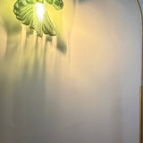 Arc Arise Standing Lamp, green shade lit against a wall