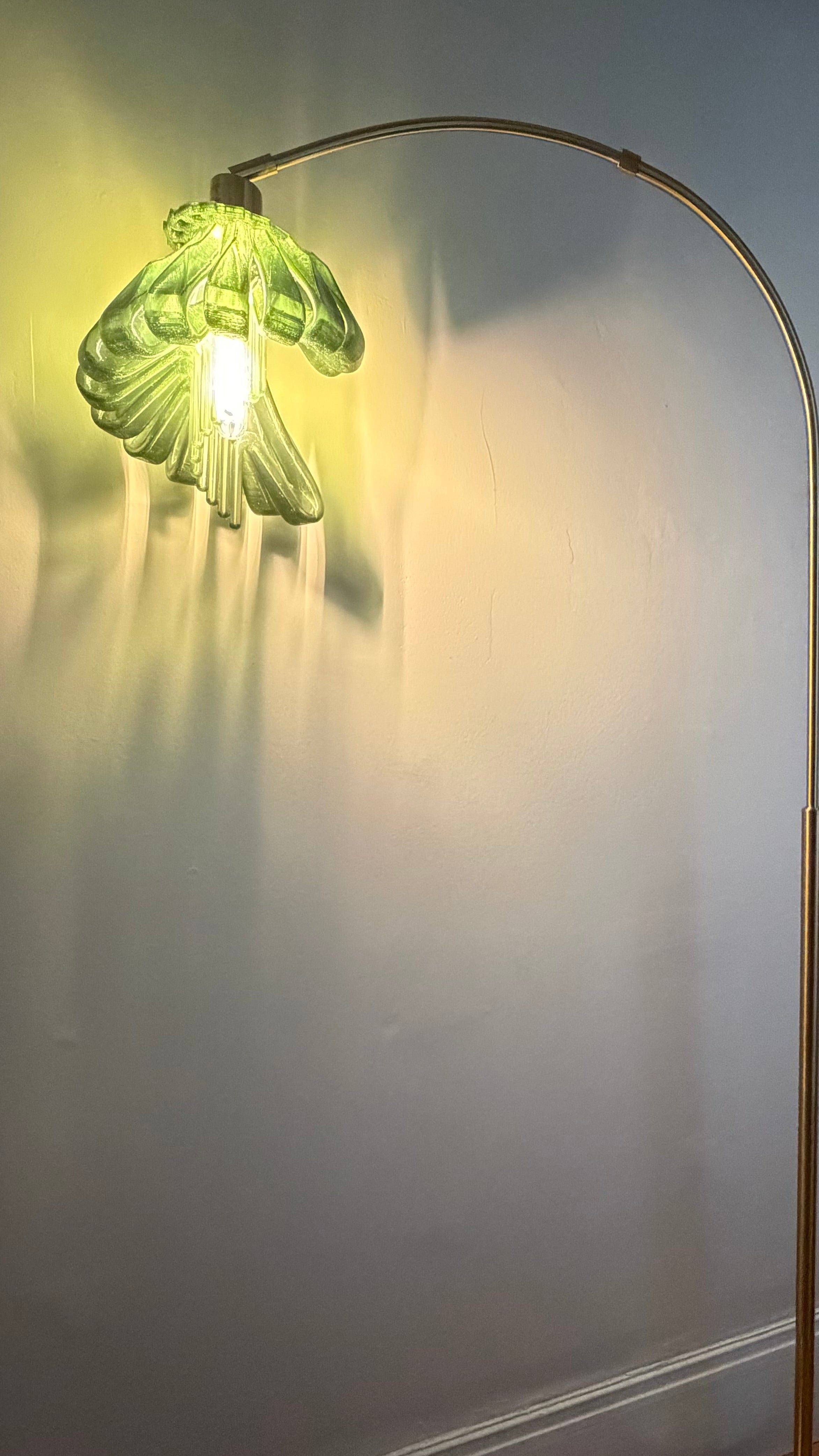Arc Arise Standing Lamp, green shade lit against a wall